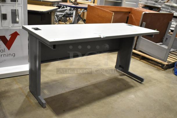 Gray desk with clean lines, T-shaped legs, and cable cutouts. Good condition, suitable for office or home use.