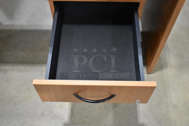 Wood pattern desk with open drawer, featuring a black handle. Part of a 3-drawer filing cabinet. Good condition.