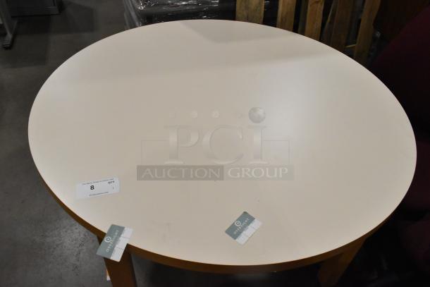 Round white table with wood pattern rim and legs, slight surface marks, auction label attached, in decent condition.