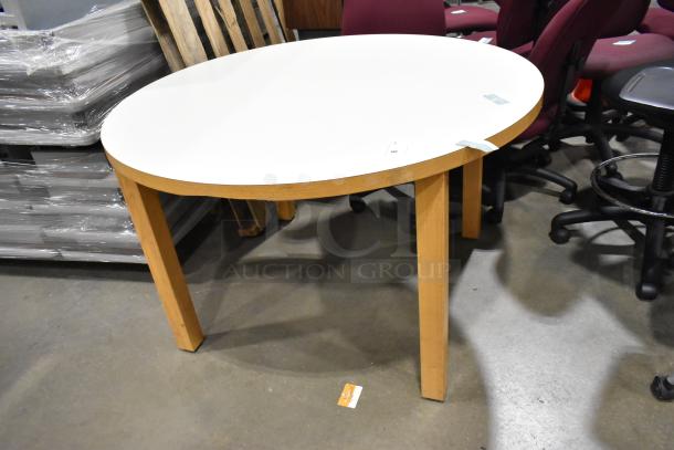 Round white table with wood pattern rim and legs, in good condition. Auction tags visible on top surface.
