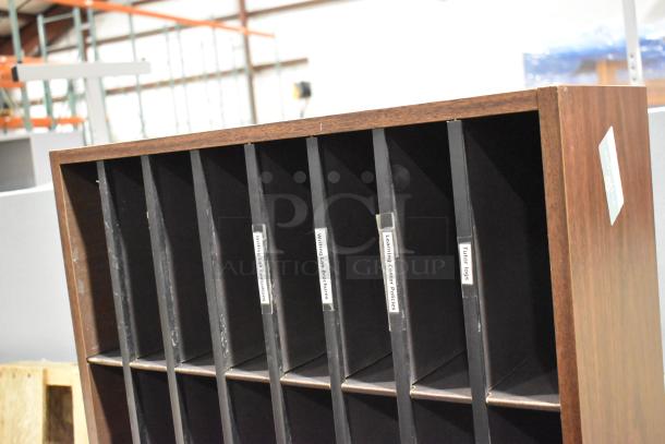Wooden 24 cubby mailer with labels "Writing Lab Evaluations," "Tutor Logs," and more. Item part of auction lot with gray 2-drawer filing cabinet.