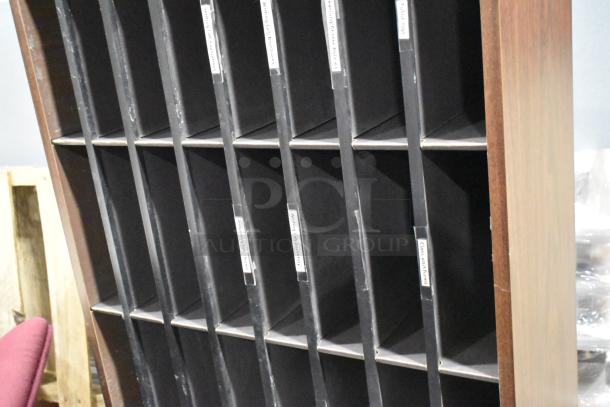 Wooden 24 cubby mailer with labeled slots, ideal for organized storage. Part of auction with gray 2-drawer filing cabinet.