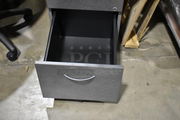 Gray two-drawer filing cabinet with open drawer, visible metal handle in warehouse setting. Good condition.