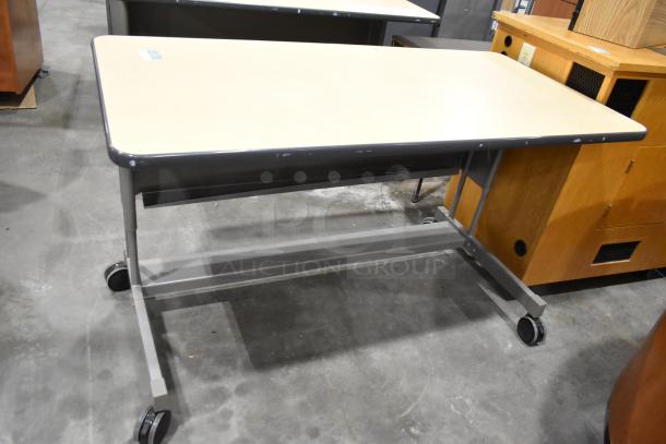 Three rolling desks with light wood tops and metal frames on casters. Great condition, adjustable height. Auction lot includes 3 desks.