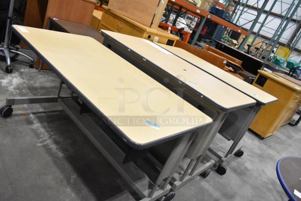 Three desks on casters, good condition, light wood tops, metal frames, suitable for office or school use.