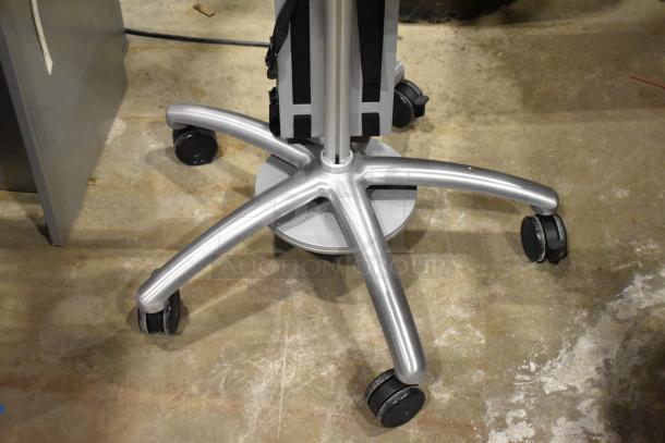 Silver portable stand with five caster wheels, sturdy metal base, in excellent condition. Ideal for equipment mobility.