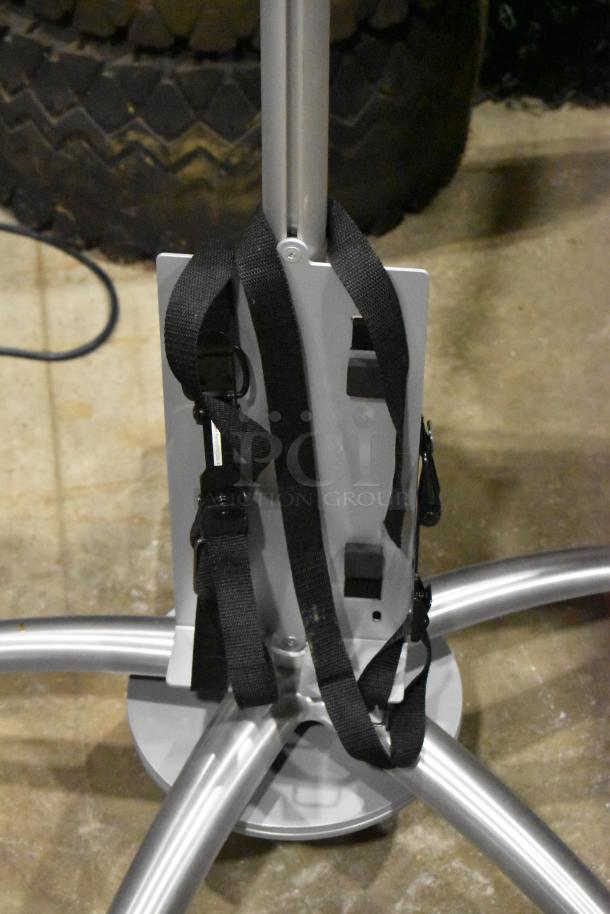 Portable stand on casters with a sturdy silver frame and black strap attachments, featuring a five-leg base for stability.