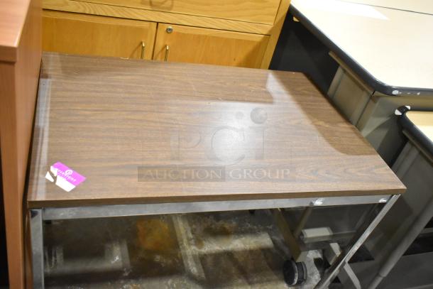 Wood-pattern table with sturdy metal legs, featuring a smooth surface. Includes label with auction info. Good condition.