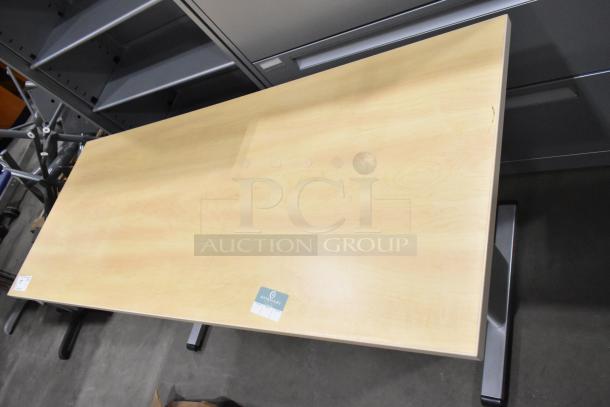 Wood pattern desk with light finish, rectangular top, and metallic legs. Minor surface wear visible. Label indicates "OpenSight".