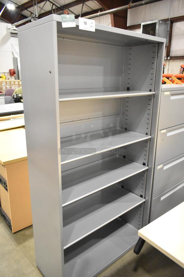Gray metal bookshelf with adjustable shelves next to a 4-drawer filing cabinet. Both items in good condition. Auction lot label visible.