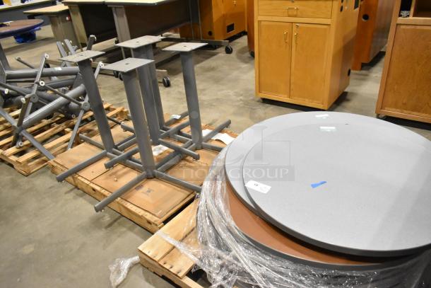 3 pallets of round gray tabletops and gray metal table legs. Items in good condition with visible packing tags.