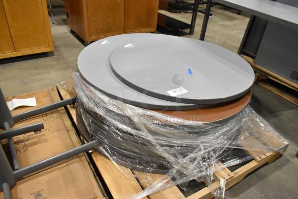 Three pallets with round gray tabletops and gray metal table legs, wrapped in plastic. Labels indicate pallet contents.