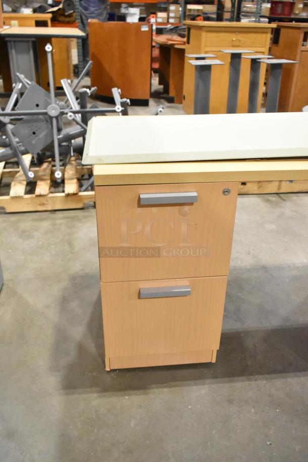 Wood pattern L-shaped desk with 2-drawer filing cabinet. Light wood finish, silver handles. In used condition.