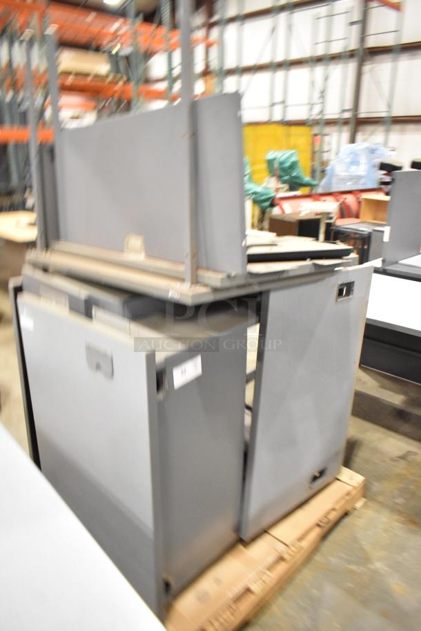 Gray desk set up with multiple compartments on pallets. Features durable construction, minor wear, ideal for office use.