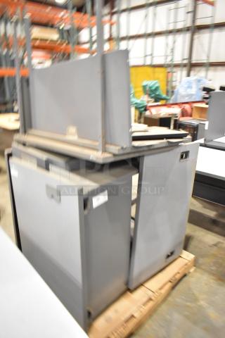 Gray desk set up with multiple compartments on pallets. Features durable construction, minor wear, ideal for office use.