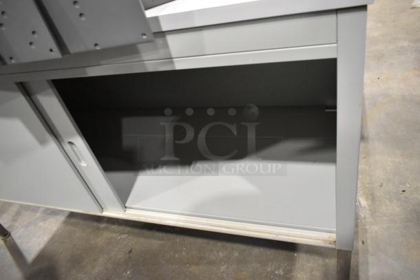 Metal 2-door cabinet, gray, with sliding doors on metal legs. Includes separate tabletop with legs. Good condition.