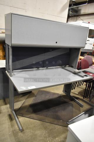 Gray desk with overhead cabinet, sleek design, durable condition, number 24 tag on surface, ideal for office use.