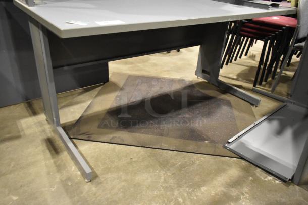 Gray desk with overhead cabinet, metal frame, adjustable feet, minor wear, ideal for office use. Tags visible on surface.
