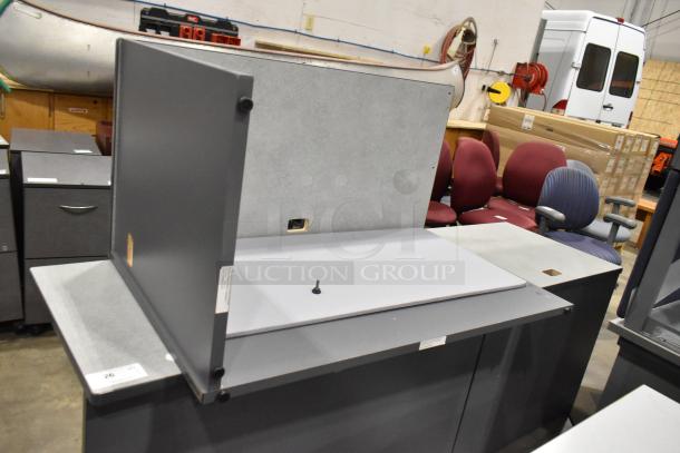 Gray desk in two pieces, featuring a smooth surface and sturdy panels. Some visible wear on edges.