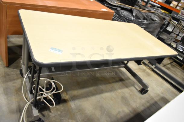 Four various desks/tables; light wood and metal legs, one with wheels. Good condition, includes cables. Auction item.