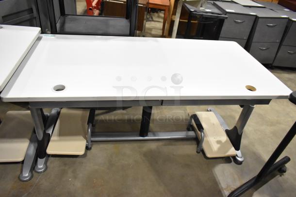 Four adjustable desks with white tops, cable management holes, and sturdy metal legs, in used condition.