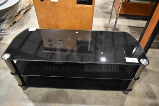 Black television stand with two under shelves, glass top, metal legs, excellent condition, small label with number 29.
