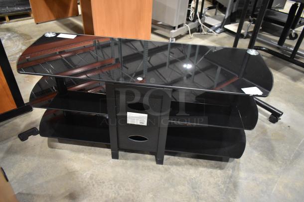 Black television stand with glass top, two sturdy under shelves, metal frame. Features labels on the central panel.