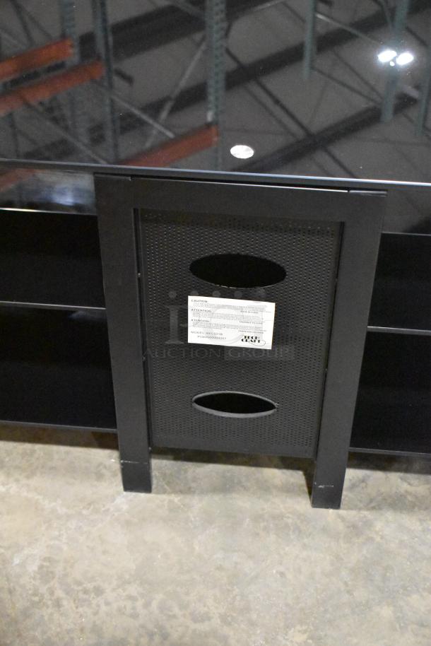 Black television stand with two shelves, features a perforated back panel with cable management openings, good condition.