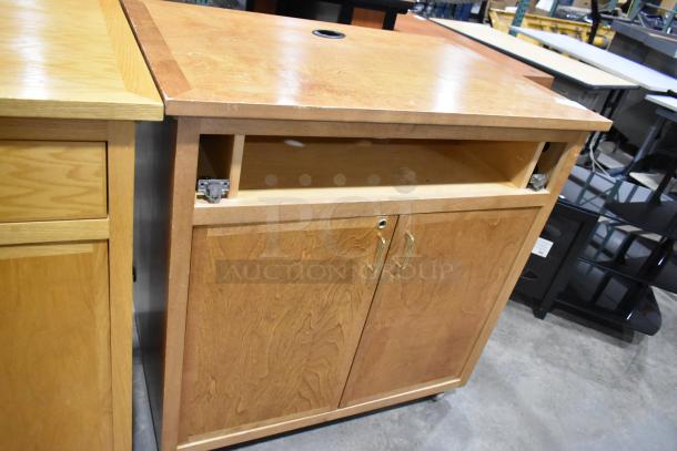 Wood pattern counter with two doors and one missing drawer. Features metal handles and a circular cord cutout on top.