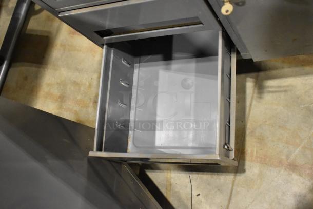 Gray metal cart with four drawers and a door, featuring commercial casters, shown open in used condition.