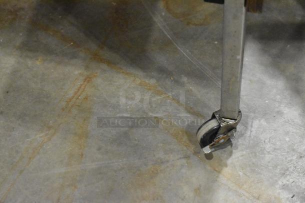 Close-up of a caster on a wood-pattern desk. Other items include a wood-pattern table and bookshelf.