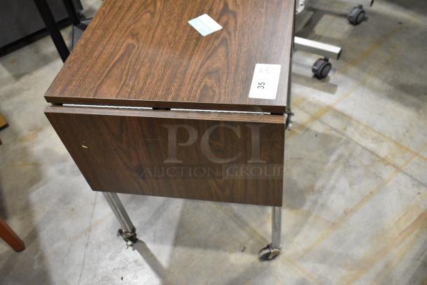 Wood pattern desk on casters, with visible tag indicating lot number 35; in used condition.