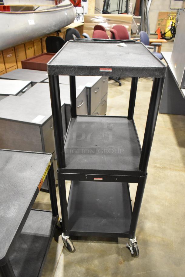 Three black carts on casters, including two AV carts. Used condition, featuring sturdy shelves and visible labels.