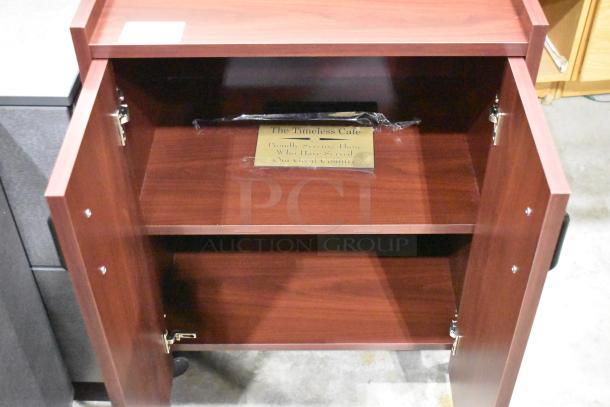 4-piece auction: 3 gray 2-drawer filing cabinets with casters, 1 wood-pattern 2-door cabinet; displays “The Timeless Cafe” plaque.