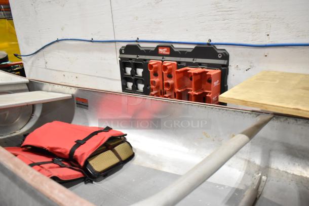 Grumman 13' metal canoe with oar and life jacket, sturdy condition. Interior shows red life jacket and oar placement.