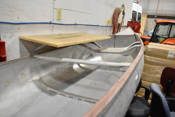 12' Grumman 13 CANOE metal canoe with oar and life jacket, in used condition, showcasing a sturdy aluminum build.