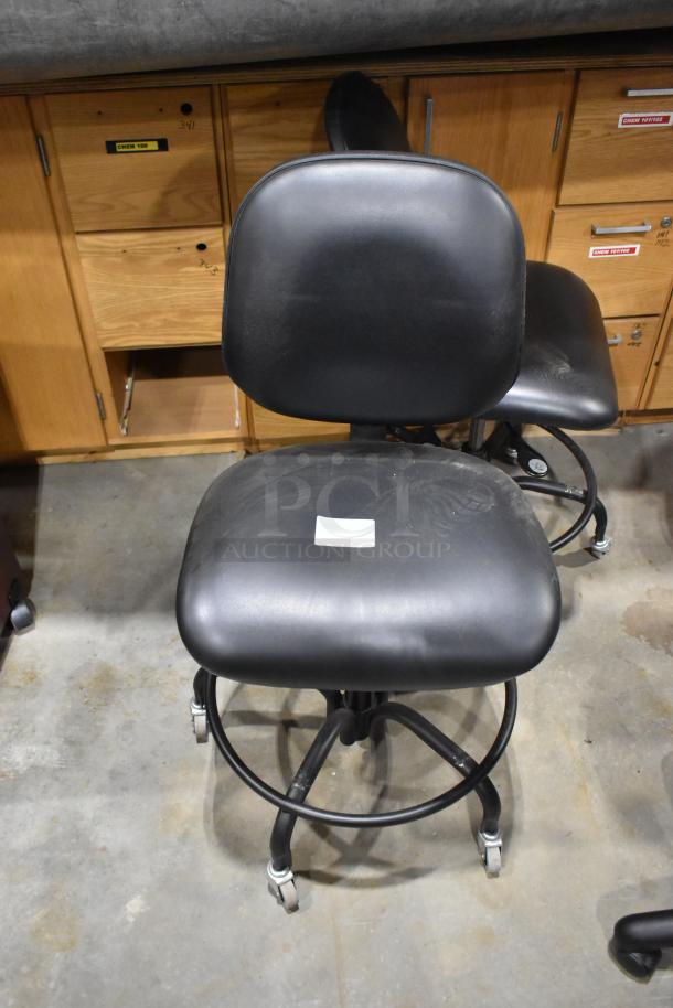 10 black office chairs with casters, ergonomic design, adjustable height, and minor wear. Includes label on seat.