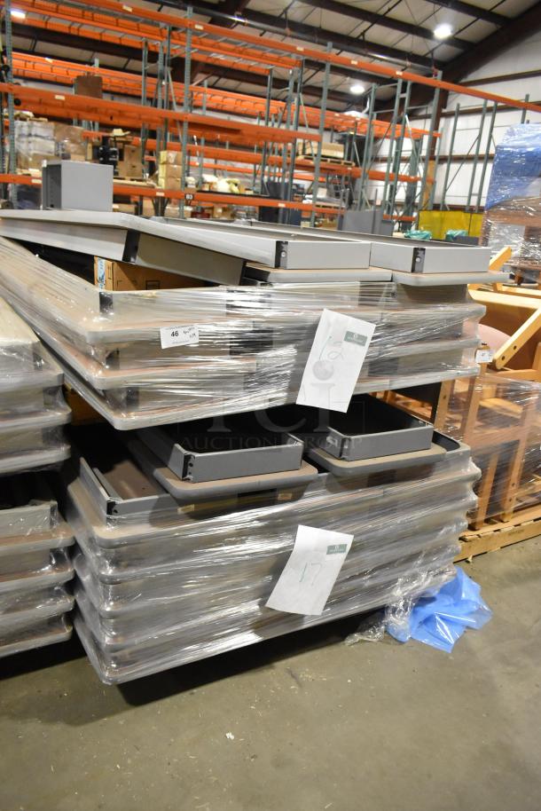 Stack of 29 gray folding tables, wrapped in plastic, in a warehouse setting. Tags indicate lot numbers.