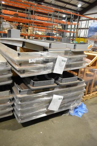 Stack of 29 gray folding tables, wrapped in plastic, in a warehouse setting. Tags indicate lot numbers.