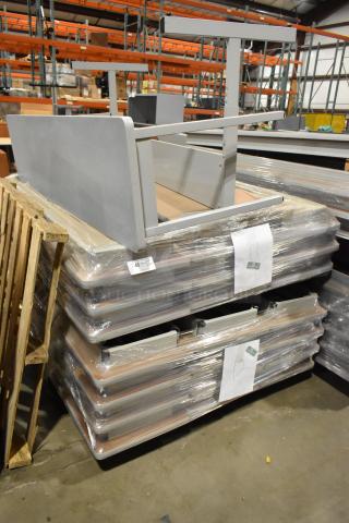 Stack of gray folding tables and a desk, shrink-wrapped, labeled with auction lot number in warehouse.