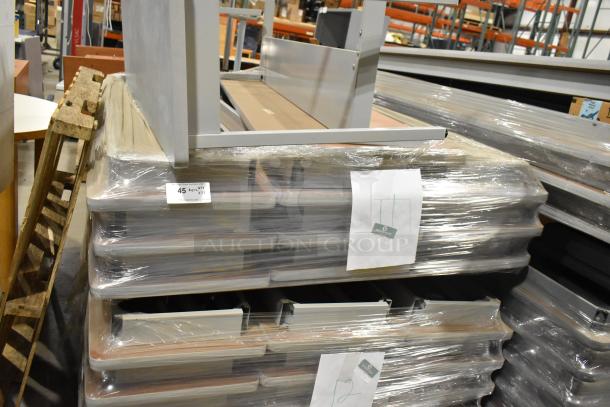 Stacked gray desk and 22 folding tables in plastic wrap, label showing quantity 23, auction item 45.