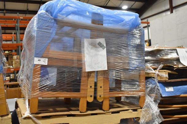 16 wood pattern chairs wrapped in plastic, labeled as Lot 49. Stack on wooden pallets in warehouse, blue cover visible.