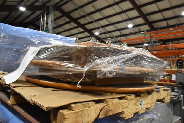 10 wood pattern tables wrapped in plastic on a pallet, ready for auction, in a warehouse setting.