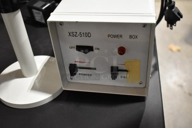 Black table with XSZ-510D power box for Pro Microscope, showing controls for pointer and field; teaching microscope setup.