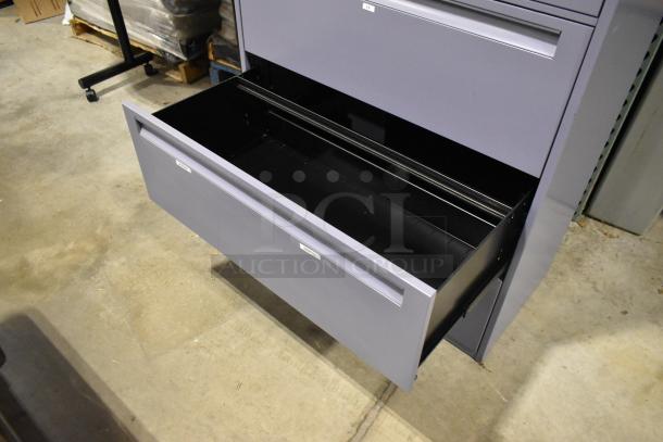 Metal filing cabinet with 4 drawers and 1 door, shown with one drawer open. Grey color, well-maintained condition.