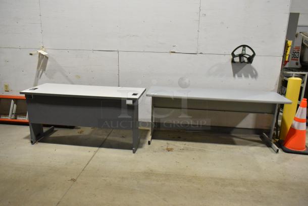 Two gray office desks, rectangular, metal legs, good condition, ideal for workspace or home office.