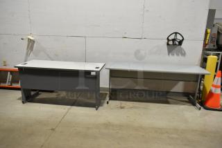 Two gray office desks, rectangular, metal legs, good condition, ideal for workspace or home office.
