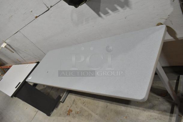 Two gray desks with simple design and sturdy construction, visible wear, ideal for office or home use.