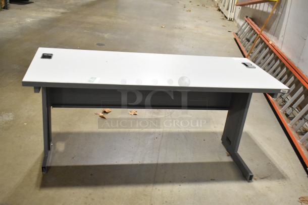 Two gray desks, sturdy metal legs, rectangular shape, cable management cutouts, good condition. Auction includes both desks.