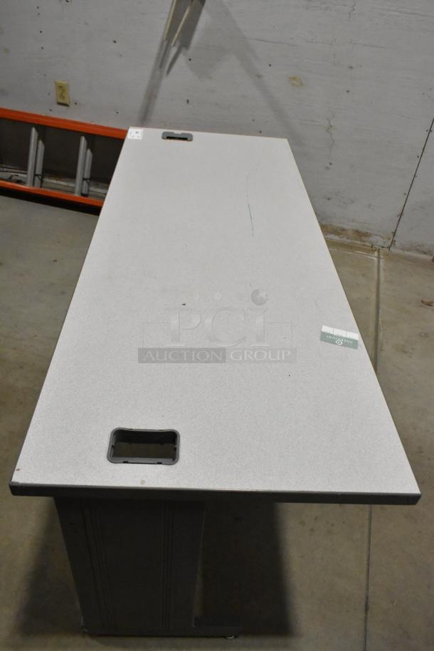 Gray desk with simple design, featuring cable cutouts and minor surface marks. Auction includes two desks.